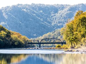 New River Gorge wide canyon water river lake during autumn golden orange foliage in fall by Grandview with peaceful calm tranquil day, closeup of bridge