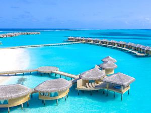 collection of Maldivian overwater bungalows with a light blue ocean beneath them