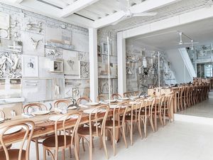 long wooden tables with chairs in an all white restaurant dining room