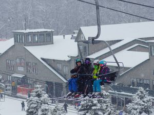 A family on a ski lift with the resort in the background