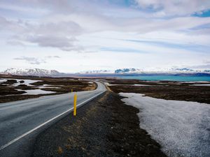 The ring road curving around the coast of Iceland with snow capped mountains in the back