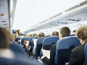 Airplane aisle with group of passengers in seats