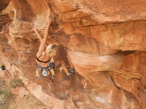 A rock climber ascends a red rock face in Nevada.