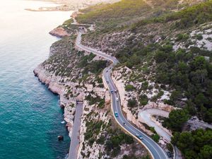 Aerial picture taken with drone flying over a traffic road in the coast with cliffs.