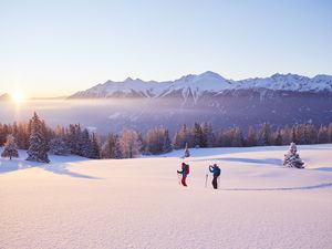 Austria, Tyrol, couple snowshoeing at sunrise