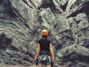 Climber woman standing in front of a stone rock outdoor