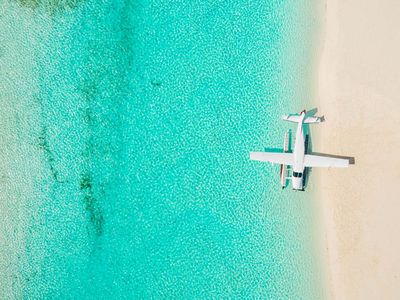 Overhead shot of a seaplane on the beach shoreling with bright blue water and white sand beaches