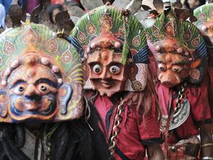 people wearing colorful traditional masks with prominent eyes as part of a festival