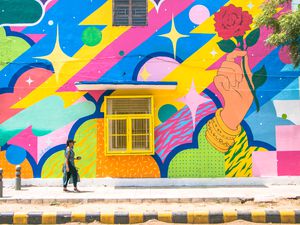 Woman walking by a colorful street mural in Lodhi Colony