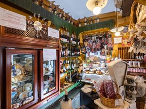 View of a cluttered restuarant with many bottles of wines, cheeses, and cured meats