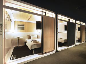 four pod-style hotel rooms in a row with a bed and side table inside