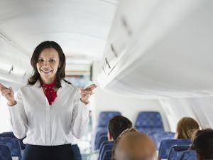 Flight attendant indicating exits in airplane