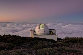 A planetarium on a hill sitting above clouds