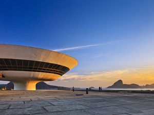 white spaceship-like buildings with large windows at sunset with the brazilian sugarloaf mountians in the background