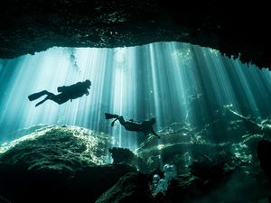 Two divers swim through a cenote in Mexico 