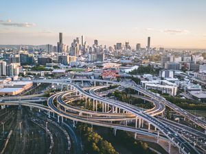 Drone shot of Brisbane with freeway intersection in foreground and city skyline in background