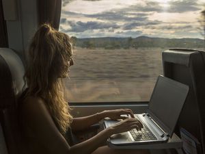 A woman works on her laptop while traveling on a train