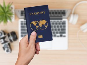 Close up of hand holding passport over computer