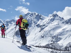Two people ski touring on mountain skis and splitboard on a slope