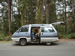 A father sitting in a retro van with his daughter, while stopped on the side of the road.
