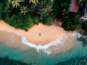 Loving couple on a secluded picturesque beach in tropical Sri Lanka surrounded by waves and palm trees