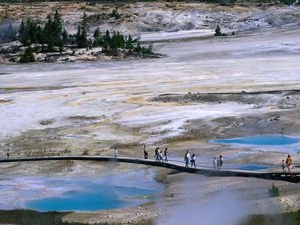 Hikers walk through the geysers of Yellowstone National Park on a boardwalk
