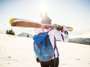 Young woman after skiing on sunny day with backpack