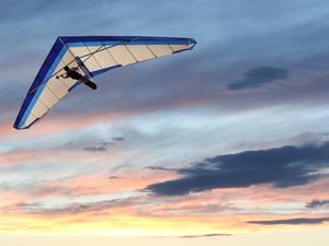 A hang glider in flight with the sun setting