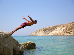 A man leaps off a high cliff into the ocean below