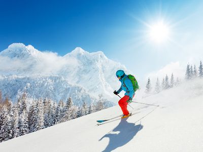 Skier in fresh powder snow running downhill