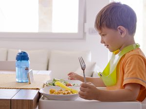 Boy watching phone while having breakfast at home.