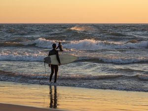 Surfers on Lake Michigan beach at sunset, Grand Haven, Ottawa County, Michigan, USA