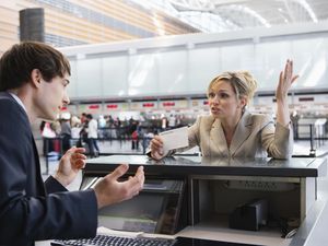 Upset businesswoman checking in at airport ticket counter