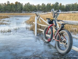 a fat bike on icy stream leaning against a wooden fence