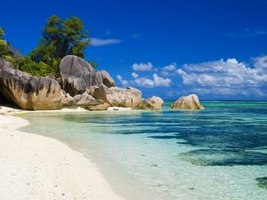 White-sand beach with Multi-hued blue water an large boulders in the Seychelles