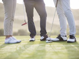 Legs and feet of three people on golf course
