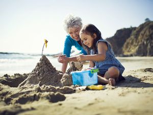 Vacation with grandchildren, grandma and grandchild playing on the beach