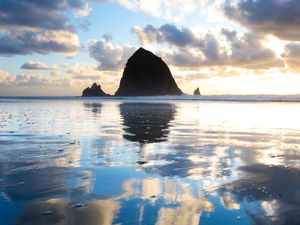 Haystack Rock reflected in the water during sunset