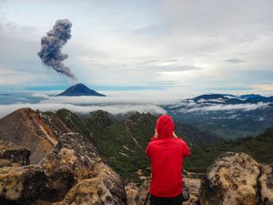 A person hiking in Sumatra watches an active volcano