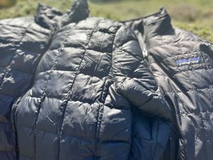 A Northface Puff jacket laying on top of a Patagonia puff jacket outside