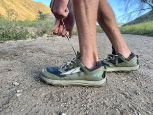 Person lacing up the Altra Lone Peak 6 Trail Running Shoes outdoors