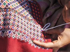 Close up of hands embroidering a scarf in Kutch