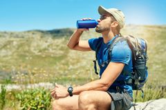 Cropped shot of a young man taking a break to drink water while out on a hike