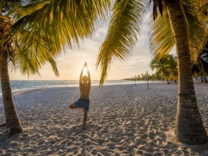 Man practicing yoga on a tropical beach at sunset in the Caribbean