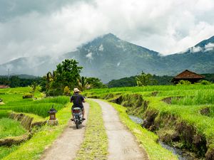 A man riding a motorbike through the countryside of Bali