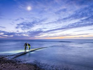 Night at beach, two night divers on the trestle road