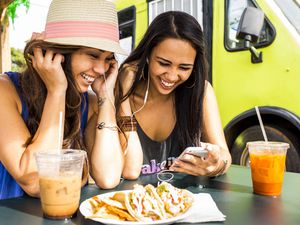 Pacific Islander women using cell phone near food cart