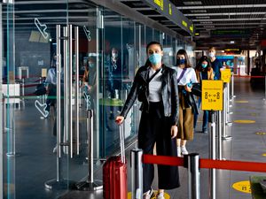 Passengers wearing N95 face masks waiting in line at airport terminal