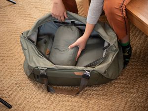open duffel bag with a person placing packing cubes into it