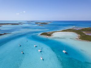 White boats float in the blue waters off the Exumas in the Bahamas